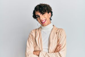 Young man wearing woman make up and woman clothes happy face smiling with crossed arms looking at the camera. positive person.